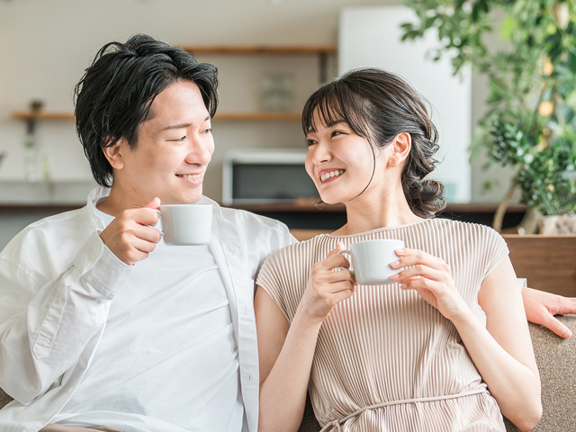 コーヒーを持ち笑顔で会話する若い夫婦